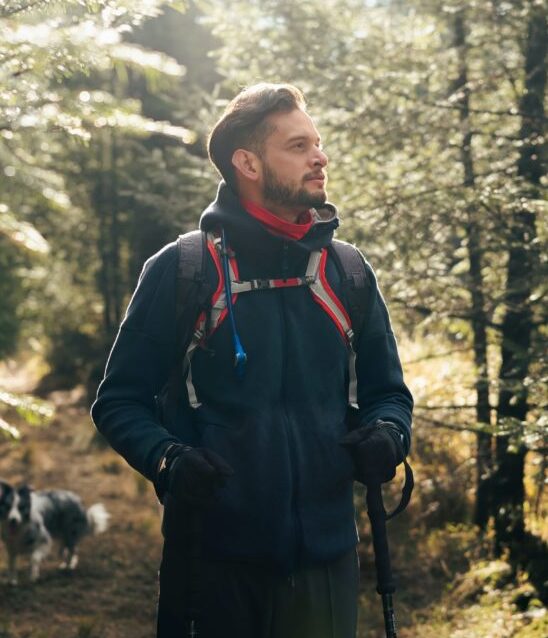 Man in a blue shirt and backpack in the forest