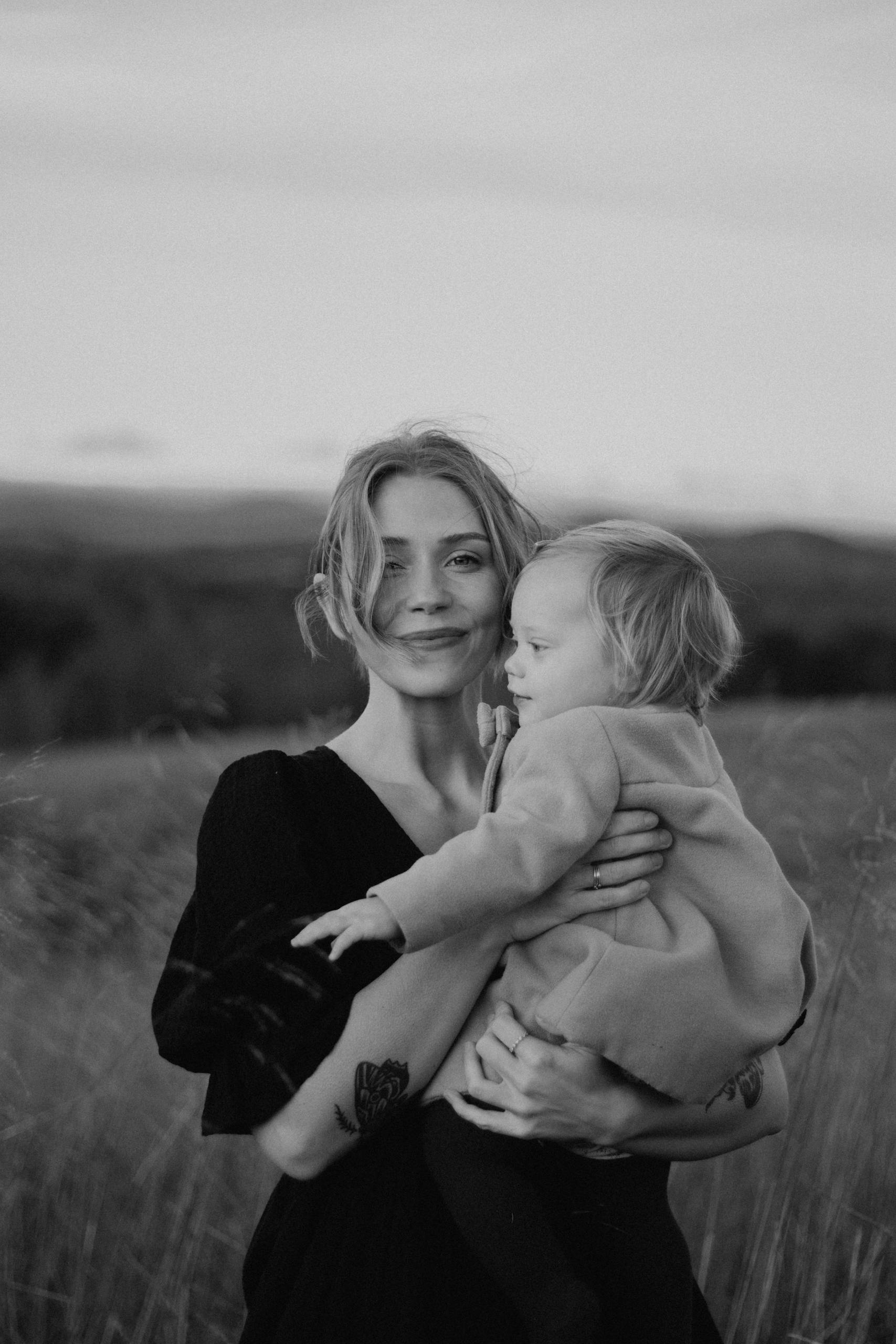 A touching black and white photo of a mother holding her child in a serene outdoor setting.
